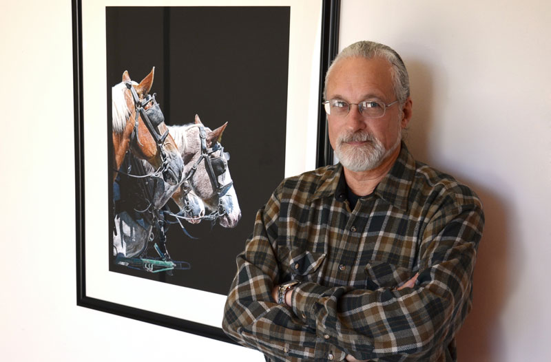 Ted Smusz poses with a piece of his donated artwork that was installed near equine receiving in the Virginia-Maryland College of Veterinary Medicine's Large Animal Hospital.