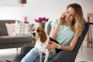 Young woman talking on phone while petting her dog.