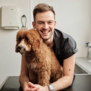 Man smiling with a fluffy dog.